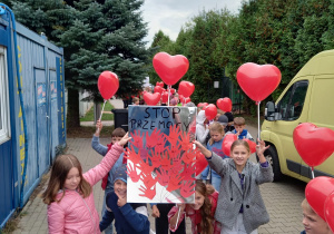 uczniowie klas 1-3 podczas marszu przeciw przemocy prezentujący wykonany plakat